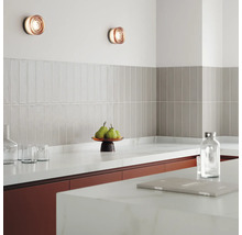 Küchenszene mit Wandleuchten, Fliesen und Küchenutensilien auf der Arbeitsplatte.