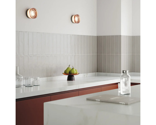 Küchenszene mit Wandleuchten, Fliesen und Küchenutensilien auf der Arbeitsplatte.