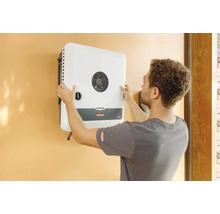 Ein Mann montiert einen Fronius GEN24 Wechselrichter an einer Wand