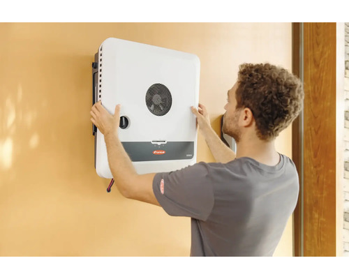 Ein Mann montiert einen Fronius GEN24 Wechselrichter an einer Wand