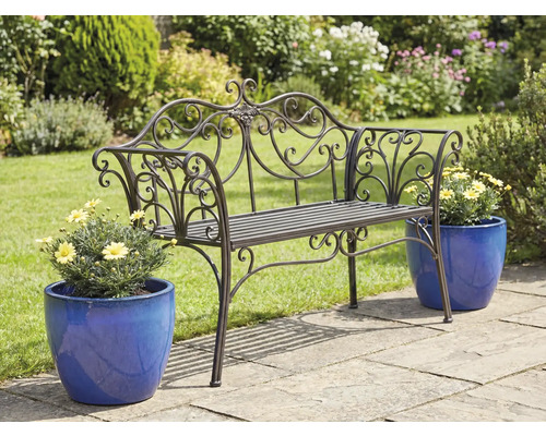 Verzierter Metalgartenbank mit Blumentöpfen auf einer Gartenterrasse