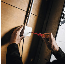 Elektriker arbeitet mit Schraubendreher an Verteilerdose