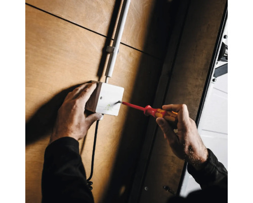 Elektriker arbeitet mit Schraubendreher an Verteilerdose