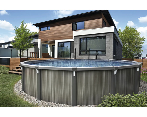Freistehender runder Gartenpool mit grauer Verkleidung in Holzoptik vor einem modernen Haus mit Holzfassade.