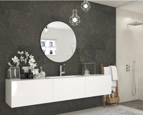 Modernes Badezimmer mit dunklen Wandfliesen in Steinoptik, weißem Hängeschrank, rundem Spiegel und begehbarer Dusche.