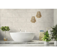 Modernes helles Badezimmer mit freistehender weißer Badewanne vor einer Wand aus großen Fliesen in Marmoroptik und zwei Pendelleuchten aus Holz.