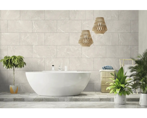 Modernes helles Badezimmer mit freistehender weißer Badewanne vor einer Wand aus großen Fliesen in Marmoroptik und zwei Pendelleuchten aus Holz.