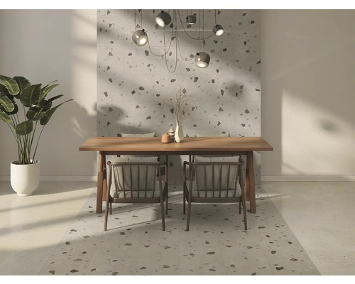 Modernes Esszimmer mit großformatigen Wand- und Bodenfliesen in Terrazzo-Optik, hellem Holztisch, Stühlen und einer Zimmerpflanze.
