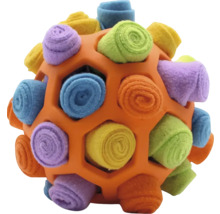 Oranger Gitterball für Hunde mit bunten, eingerollten Vliesstreifen als Schnüffelspielzeug.