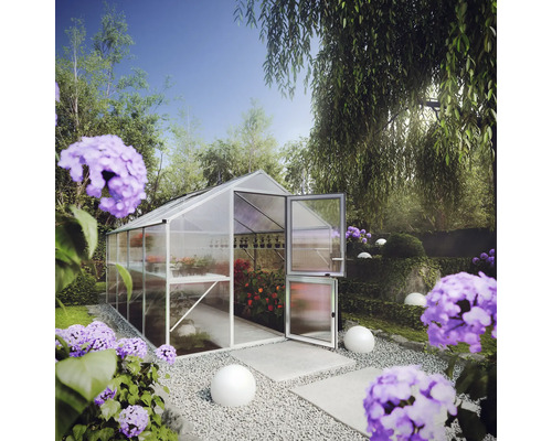 Modernes Gewächshaus mit Aluminiumrahmen und Hohlkammerplatten in einem Garten. Die geteilte Tür ist offen und zeigt Pflanzen auf Regalen.