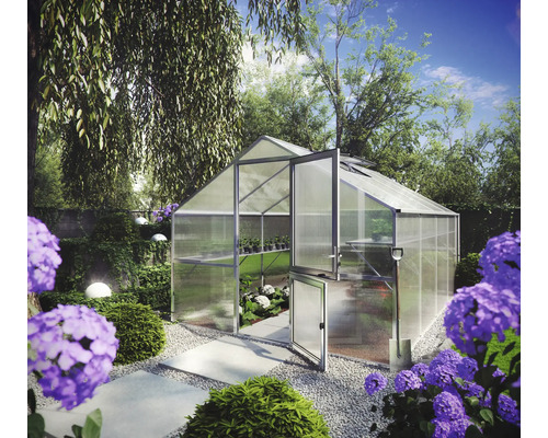 Gewächshaus aus Aluminium und Polykarbonat mit geteilter Tür in einem hellen Garten mit Blumen und Gehwegen.