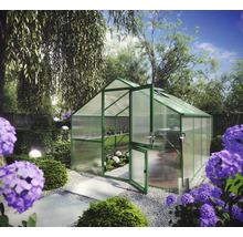 Helles Gewächshaus mit grünem Aluminiumrahmen und Hohlkammerplatten in einem organisierten Garten mit Blumen und Steinplattenweg.