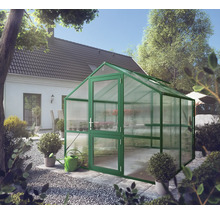 Freistehendes Gewächshaus mit grünem Aluminiumrahmen und Hohlkammerplatten in einem Garten neben einem Wohnhaus.