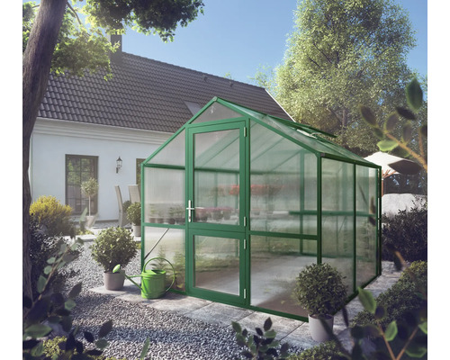 Freistehendes Gewächshaus mit grünem Aluminiumrahmen und Hohlkammerplatten in einem Garten neben einem Wohnhaus.
