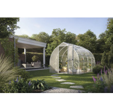 Modernes bogenförmiges Gewächshaus mit lichtdurchlässigen Paneelen in einem weitläufigen Garten mit Rasen, Steinpfad und Außenterrasse.