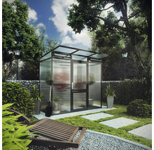 Modernes Gewächshaus mit dunklem Metallrahmen und Milchglaspaneelen in einem gestalteten Garten mit Steinweg und Pflanzen.