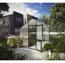 Modernes Gewächshaus mit Satteldach, schwarzem Aluminiumrahmen und Polycarbonatplatten in einem gepflegten Garten neben einem Wohnhaus.