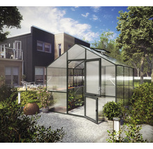 Modernes Gewächshaus aus Aluminium mit Stegplatten im Garten neben einem Wohnhaus, mit Pflanzenregalen und geöffneter Tür.