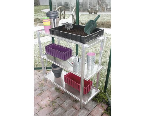 Dreistöckiges Aluminium-Gewächshausregal mit Gartenutensilien wie einer Pflanzschale mit Erde, einer Gießkanne und verschiedenen Pflanztöpfen.