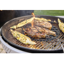 Zwei Steaks und gefüllte Maiskolben auf einem Holzkohlegrill mit eingestecktem Fleischthermometer.