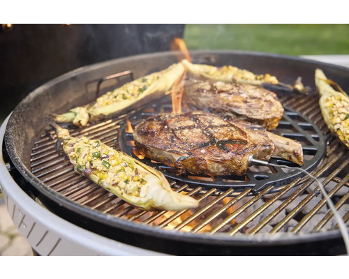 Zwei Steaks und gefüllte Maiskolben auf einem Holzkohlegrill mit eingestecktem Fleischthermometer.