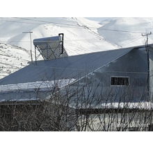Solarthermie-Anlage mit Vakuumröhren und Speicher auf einem Metalldach in einer winterlichen Berglandschaft.