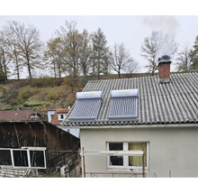 Zwei Solarthermie-Anlagen mit Vakuumröhrenkollektoren und integrierten Wassertanks auf einem Hausdach.