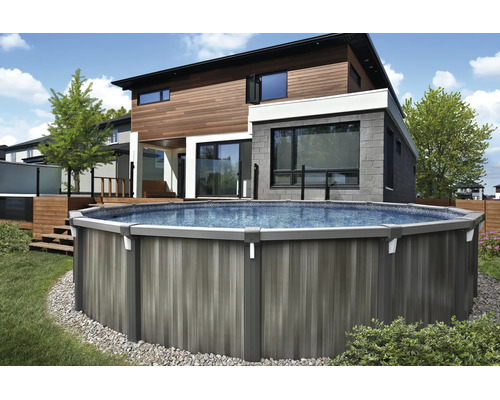 Großer runder Aufstellpool mit Paneelen in Holzoptik in einem modernen Garten neben einem Haus mit Holzterrasse und Rasen.