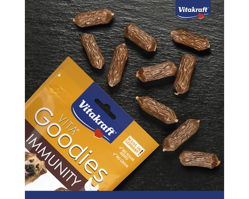 Vitakraft Vita Goodies Immunity Hundesnacks, getreidefrei und ohne Zuckerzusatz, kleine würstchenförmige Belohnungen neben der Verpackung.