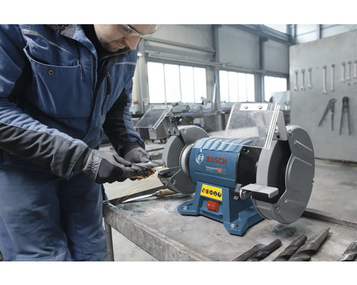 Bosch Professional Doppelschleifer in einer Werkstatt, ein Handwerker schärft ein Werkzeug mit Funkenflug.