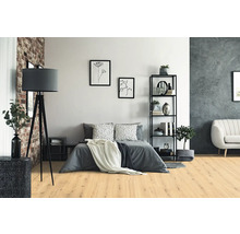 Modernes Schlafzimmer mit hellem Boden in Eichenoptik, grauem Bett, schwarzer Dreibein-Stehleuchte und Metallregal.