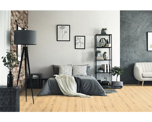 Modernes Schlafzimmer mit hellem Boden in Eichenoptik, grauem Bett, schwarzer Dreibein-Stehleuchte und Metallregal.