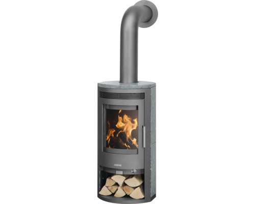 Justus Kaminofen mit Specksteinverkleidung, Sichtscheibe mit brennendem Feuer, Ofenrohr und Holzfach mit Brennholz.