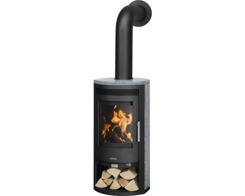 Justus Kaminofen mit Specksteinverkleidung, Sichtscheibe mit loderndem Feuer, schwarzem Ofenrohr und Holzfach mit Holzscheiten.