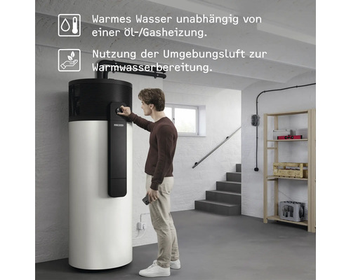 Ein Mann bedient eine Stiebel Eltron Warmwasser-Wärmepumpe im hellen Keller, die unabhängig von Öl und Gas mit Umgebungsluft Wasser erwärmt.