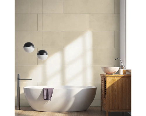 Modernes Badezimmer mit großen beigen Wandfliesen, freistehender weißer Badewanne, hölzernem Waschtischunterschrank und kugelförmigen Pendelleuchten.