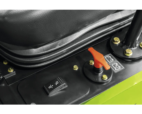 Bedienpanel einer Baumaschine mit orangefarbenem Batterietrennschalter und schwarzem Wippschalter neben dem Sitz.