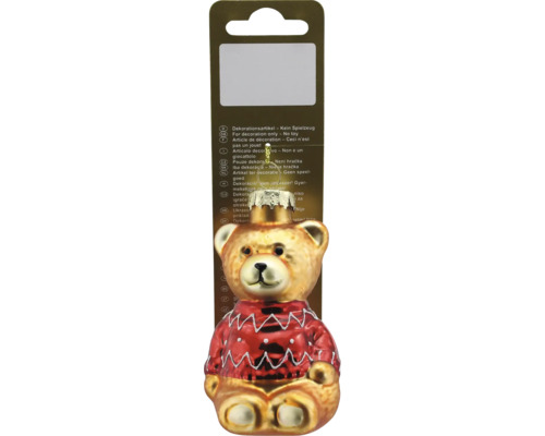 Christbaumschmuck aus Glas in Form eines Teddybären mit rotem Pullover und Aufhänger auf einer Verkaufsverpackung.