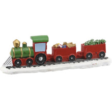 Dekorativer Weihnachtszug mit grüner Lokomotive und roten Waggons beladen mit Geschenken und Tanne auf verschneiten Gleisen.