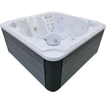 Quadratischer Außenwhirlpool mit weißer Wanne, grauer Außenverkleidung in Holzoptik und integrierten Massagedüsen.