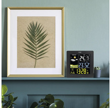 Digitale Funk-Wetterstation mit Farbdisplay, Anzeige von Uhrzeit, Innen- und Außentemperatur sowie Wettervorhersage, auf einem Regal im modernen Raum.