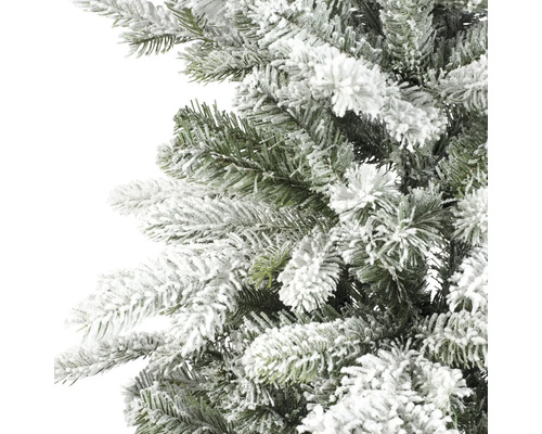 Künstliche grüne Weihnachtsbaumzweige mit weißem Kunstschnee in Nahaufnahme.