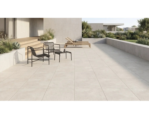 Großzügige moderne Terrasse mit hellen Terrassenplatten, schwarzen Metallsesseln, Beistelltisch, Holzliegen und bepflanzten Betonkübeln.
