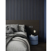 Wandpaneel aus Holzlamellen im Schlafzimmer hinter einem Bett mit grauer Bettwäsche und modernem Nachttisch.