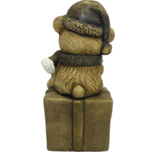 Weihnachtsfigur Bär in Rückansicht mit Weihnachtsmütze und Schal, sitzend auf einem Geschenkpaket.