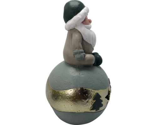 Weihnachtsfigur Wichtel sitzend auf einer Kugel mit dekorativem Band und Tannenbaum-Aussparung.