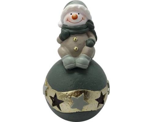 Schneemann-Figur sitzend auf einer Dekokugel mit Sternen, Weihnachtsdekoration aus Keramik.