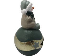 Weihnachtsfigur Schneemann in Beige und Grau, sitzend auf einer dunkelgrünen Kugel mit goldenem Sternenband.