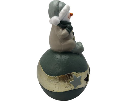 Weihnachtsfigur Schneemann in Beige und Grau, sitzend auf einer dunkelgrünen Kugel mit goldenem Sternenband.