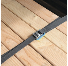 Grauer Spanngurt mit Metallschnalle sichert mehrere Holzbretter.
